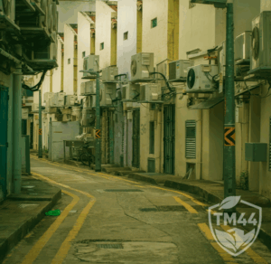 Alleyway view with multiple external air conditioning units mounted on building walls, symbolising TM44 certificate issuance and official government lodgement.